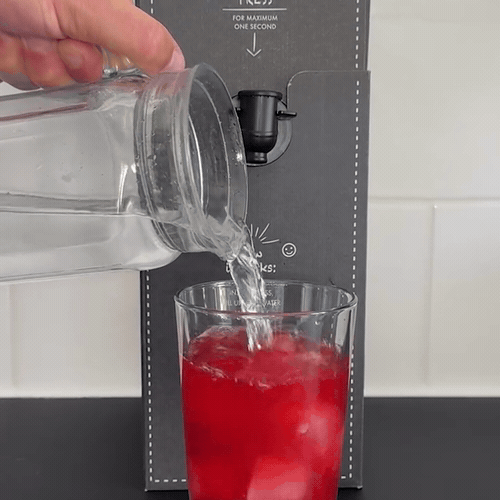 Wasser wird ins Glas nachgefüllt, das Getränk ist fertig